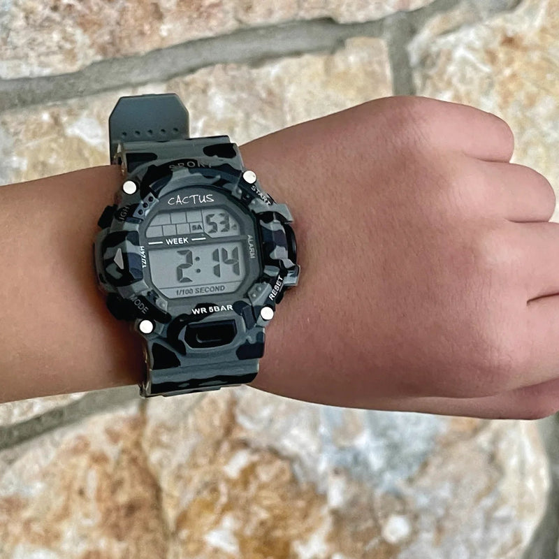 Digital camouflage watch on a wrist with a stone wall background