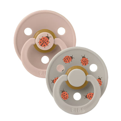 Two pacifiers with ladybug design on a black background